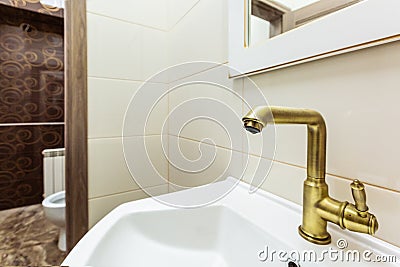 Modern cuprum faucet with falling water drop and sink in toilet room Stock Photo