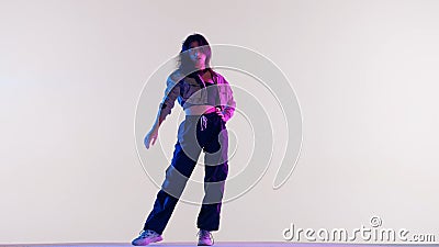 Attractive woman in white top black pants and in red and blue neon light dances jazz funk dance, isolated on white Stock Photo