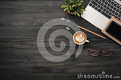 Modern dark wood office desk table with laptop, smartphone and other supplies with cup of coffee. copy space for input the text in Stock Photo