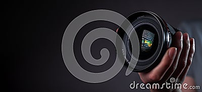 Modern digital camera wide-angled 35 mm lens in hand over dark black gray background with copy space for text Stock Photo