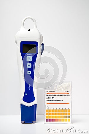 A modern digital pH meter next to a box of paper pH strips. pH measuring. Stock Photo