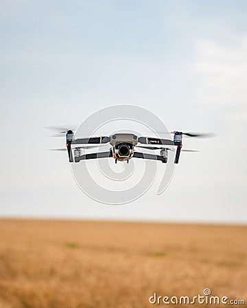 Modern drone takes flight over a vast expanse of golden wheat, highlighted by the sun Editorial Stock Photo