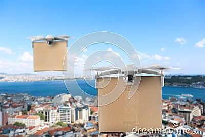 Modern drones with carton boxes flying above city on sunny day. Delivery service Stock Photo