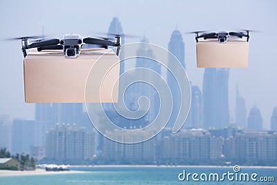 Modern drones with carton boxes flying above sea on sunny day. Delivery service Stock Photo