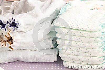 Modern eco stacks of cloth diapers and disposable diapers, pampers, selective focus close-up on bright background Stock Photo