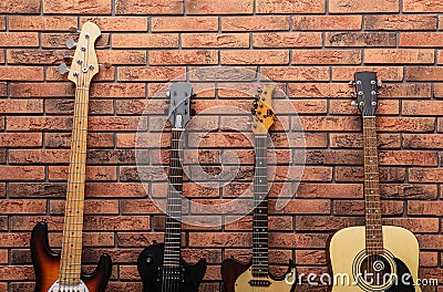 Modern electric and classical guitars near red brick wall Stock Photo