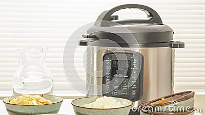 Modern electric multi cooker or Pressure cooker with some ingredients for cooking needs close up Stock Photo