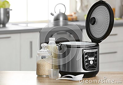 Modern electric multi cooker, rice and milk on table in kitchen. Stock Photo