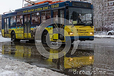 Modern electric trolley bus departing from public transport stop in the winter sunny day. Environmentally friendly transport Editorial Stock Photo