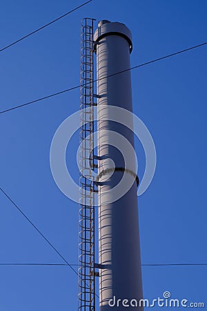 Modern exhaust pipe in an old residential area with low-rise buildings against a clean blue sky. Light gray color. Stairs. Against Stock Photo