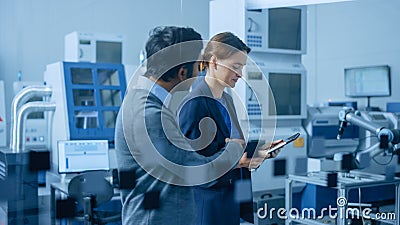 Modern Factory: Female Project Manager and Male Engineer Walk Through High Tech Development Facili Stock Photo