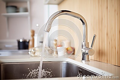 modern faucet running clear water into a sink Stock Photo