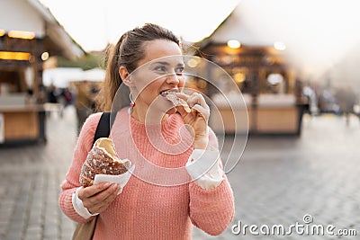 Modern female at fair in city eating trdelnik Stock Photo