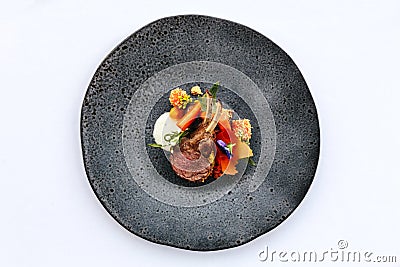 Modern French cuisine: Roasted Lamb neck & rack served with carrot, yellow curry served in black stone plate Stock Photo