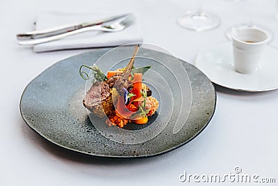 Modern French cuisine: Roasted Lamb neck & rack served with carrot, yellow curry served in black stone plate Stock Photo