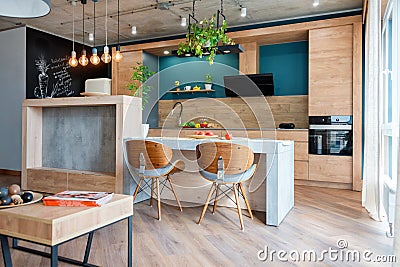 Modern furniture in luxury kitchen. Minimalist scandinavian interior in loft apartment with wooden furniture, lamps Stock Photo