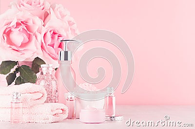 Modern gentle girlish bathroom decor - cosmetics for bath and spa, bouquet of roses, bath accessories on soft white wooden table. Stock Photo