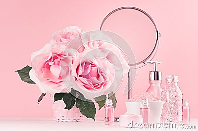 Modern gentle girlish bathroom decor - cosmetics for bath, spa, bouquet of roses, round mirror, bath accessories on white wood. Stock Photo