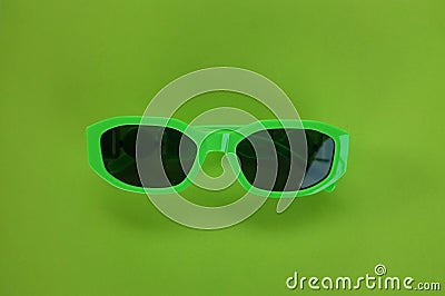 Modern green sunglasses isolate on a green background.Traveler and summer accessories Stock Photo