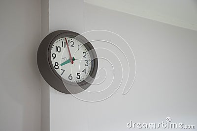 Modern clock hanged on the white wall. Stock Photo