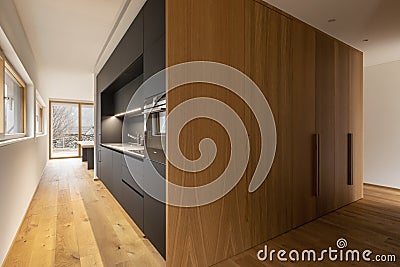 Modern home interior with white walls and a parquet on the floor. Modern black kitchen and large cupboards Stock Photo