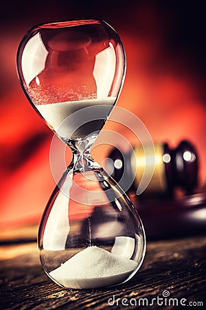 Modern hourglass in running time and justice hammer on wooden table Stock Photo