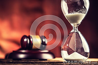 Modern hourglass in running time and justice hammer on wooden table Stock Photo