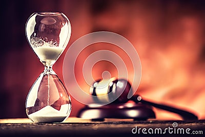 Modern hourglass in running time and justice hammer on wooden table Stock Photo