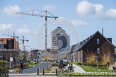 Modern houses with solarpanels on the roof ,with construction site in the background and people in the front,on a sunny day Editorial Stock Photo