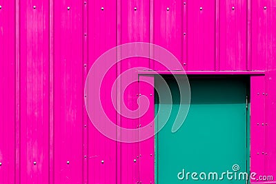 Modern industrialism. Neon pink building with green door. Vibrant paint color choice. Stock Photo