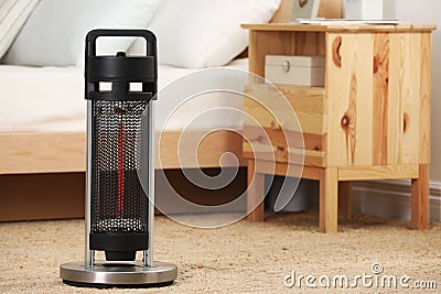 Modern infrared heater on carpet in cozy room. Space for text Stock Photo