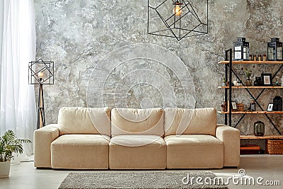 Modern interior of living room with gray walls, beige sofa, floor lamp and chandelier, light carpet shelf with frames Stock Photo