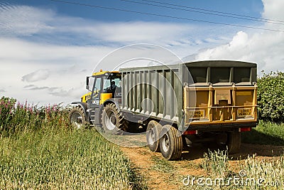 Modern JCB fast trac tractor pulling green yellow trailer Editorial Stock Photo