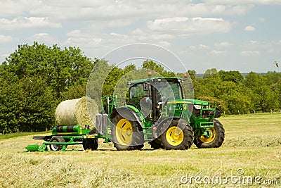 Modern John Deere green tractor with round bale wrapper Editorial Stock Photo