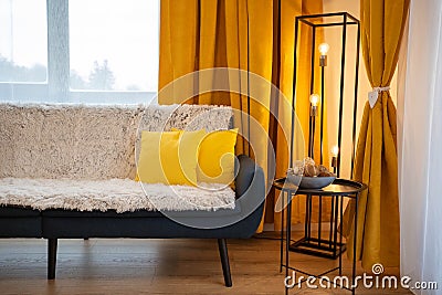 Modern living room with black coffee table, yellow pillows on dark blue coach and yellow courtains. Stock Photo