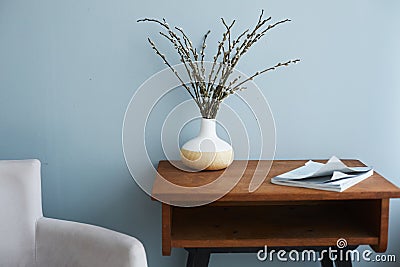 Modern living room interior, armchair by a side and wooden table with vase and fashion magazine on it Stock Photo