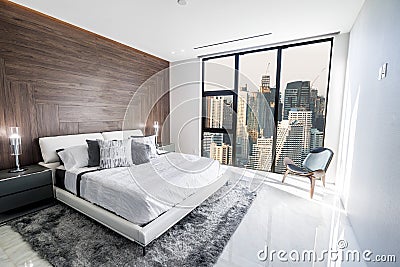 Modern and luxurious bedroom with white ceiling and wood accents with views of Bangkok skyline. Condo or Hotel accomodation Stock Photo