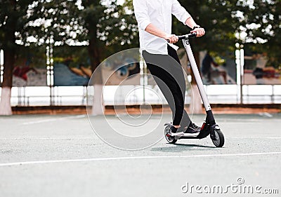 Modern man in stylish black and white outfit riding electric scooter in the city Stock Photo