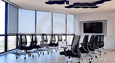 Modern meeting room with many chair, table, black television and clear window with building background. Stock Photo