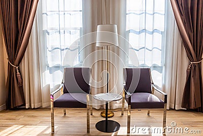 Modern metal chairs and marble tables in a room with windows and curtains Stock Photo