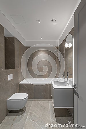 Modern minimalist bathroom beige interior design with marble tiles and beige furniture. Stock Photo