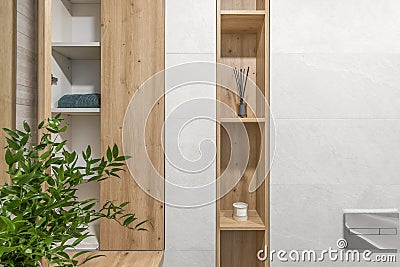 Modern minimalist bathroom interior design with ecru stone tiles and wood wall hidden shelf for bathroom accessories. Stock Photo