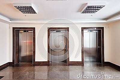 Modern minimalist business centre lobby interior with three closed steel lift doors Stock Photo