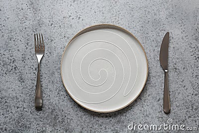 Modern modus, fork and knife on grey stone table. Minimal table place setting. Space for text or menu. View from above Stock Photo