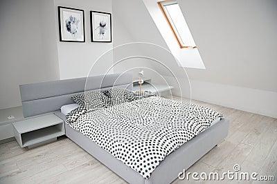 Modern monochrome design home interior of bedroom room in mansard with wooden bed and elegant accessories Editorial Stock Photo