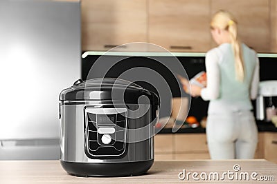 Modern multi cooker and blurred woman on background Stock Photo