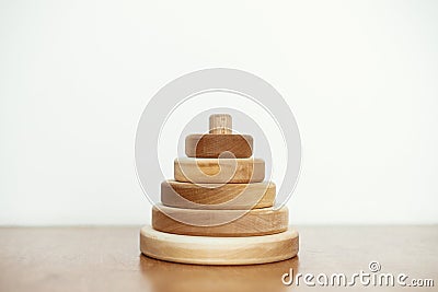Modern natural wooden pyramid with rings on table on white wall background. Eco friendly plastic free toys for toddler. Stylish Stock Photo