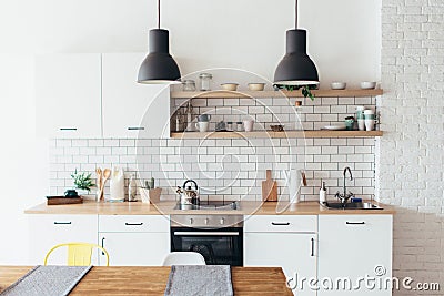 Modern new light interior of kitchen with white furniture and dining table. Stock Photo