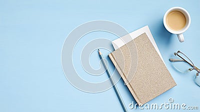 Modern office desk table with notebook, paper note, cup of coffee, pencil, glasses on blue background. Elegant feminine workspace Stock Photo
