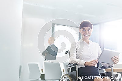 Portrait of smiling disabled businesswoman sitting with digital tablet in boardroom at office Stock Photo